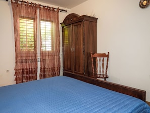 A bedroom with a bed, wooden wardrobe, and a chair. - Apartment Branka by Interhome (Mošćenička Draga)