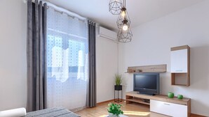 A modern living room with a sofa, a coffee table with a plant, a TV on a wooden stand, and a large window with curtains.