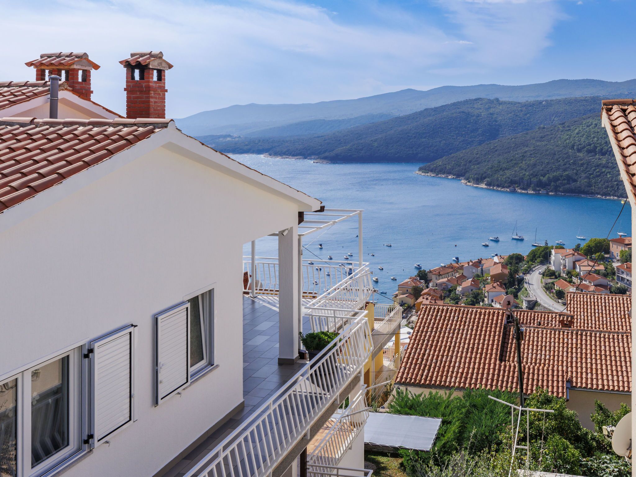A coastal building with a balcony overlooking a bay with boats.