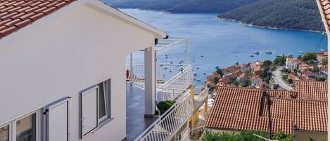 A coastal building with a balcony overlooking a bay with boats.