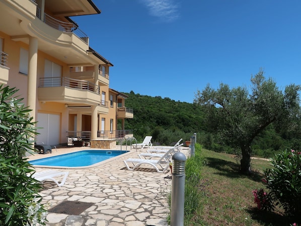 Enjoy a serene outdoor space with a swimming pool, lounge chairs, and lush greenery.