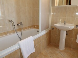 Enjoy a refreshing soak in the bathtub with a handheld showerhead and convenient pedestal sink.