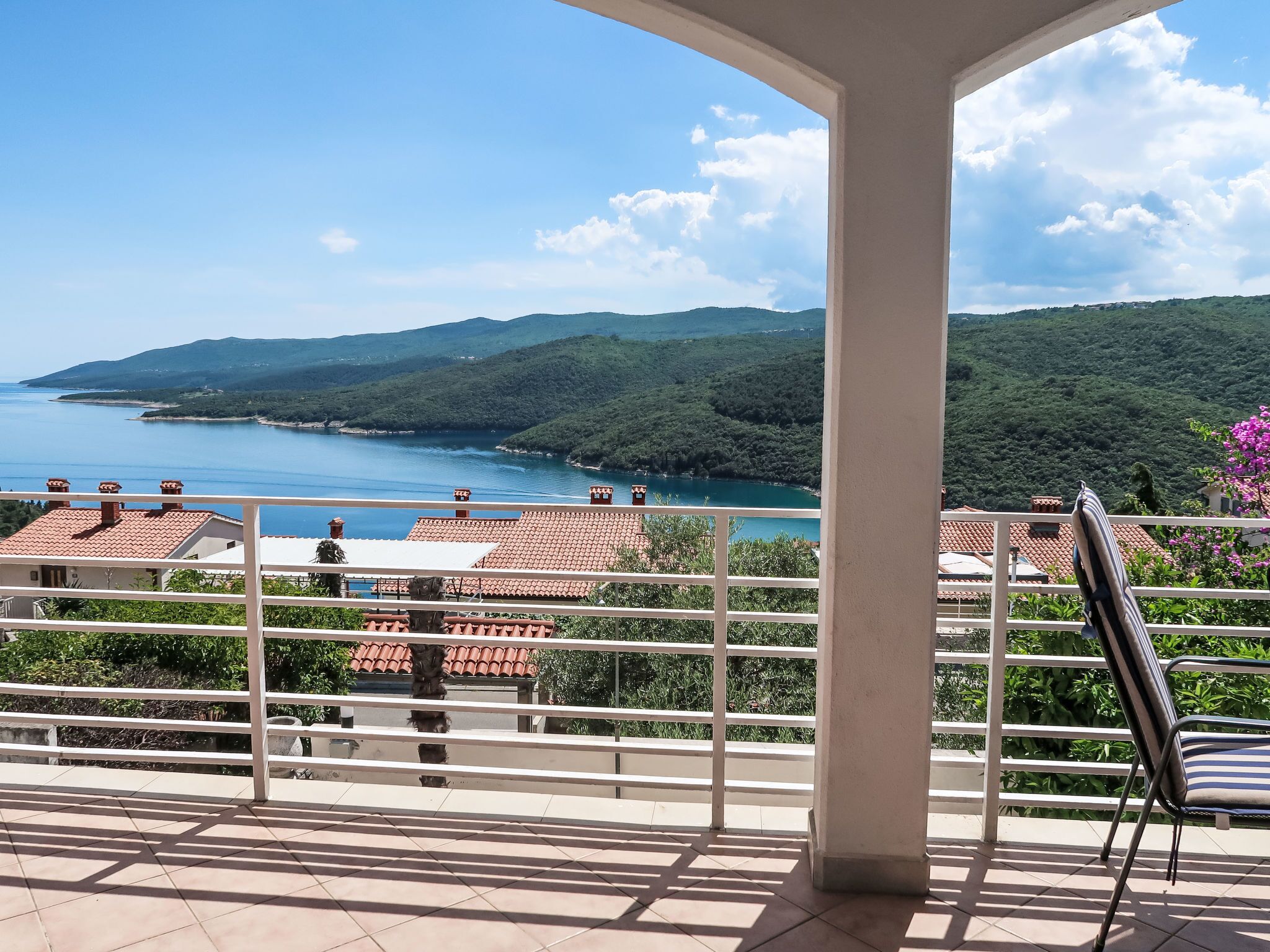 A balcony with a view of a lake and hills.