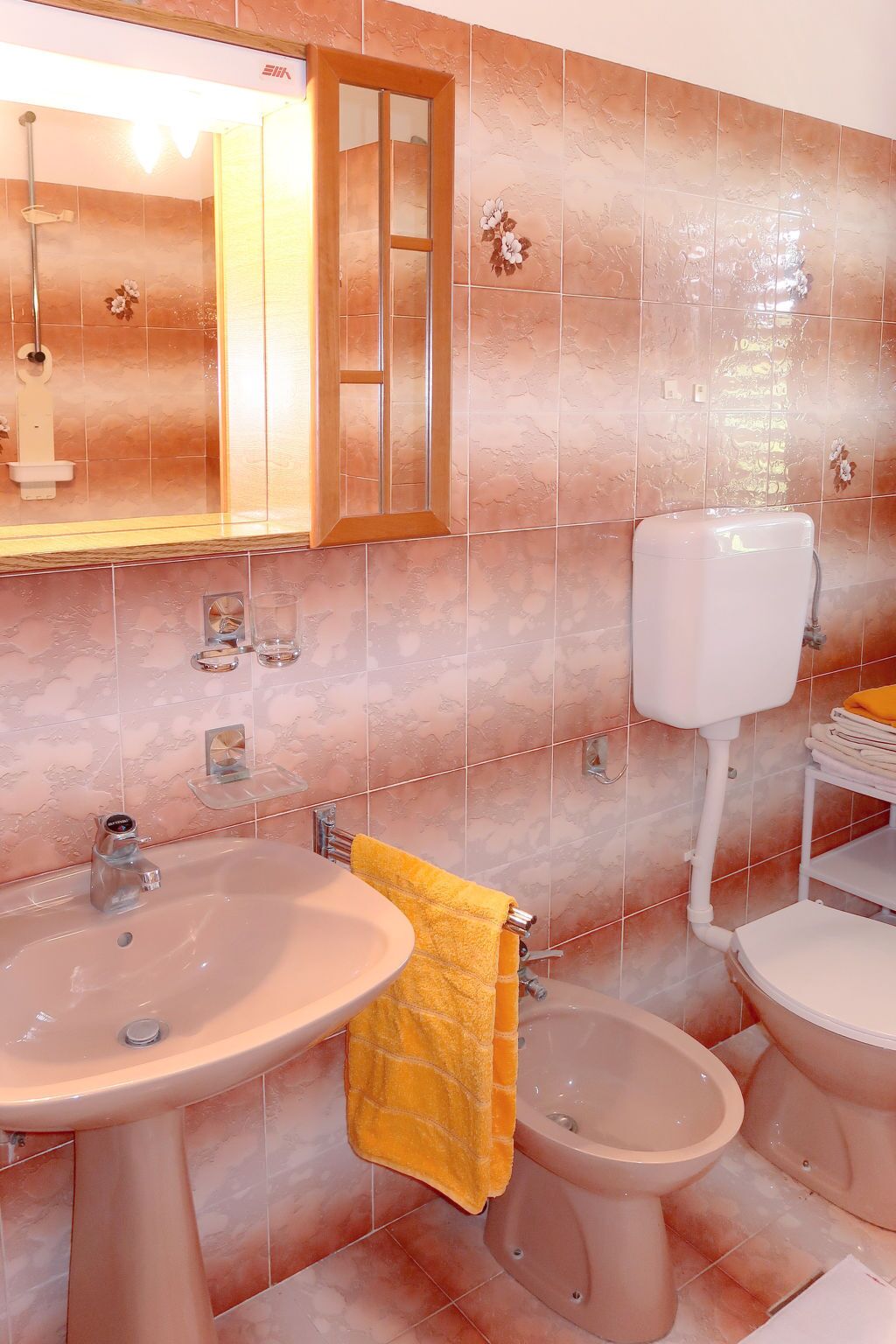 Une salle de bain équipée d’un lavabo, d’un miroir, de toilettes et d’un bidet.