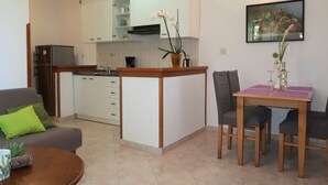 A compact kitchen with a dining area, a sofa, and a table with chairs. - Mirjana by Interhome (Labin)