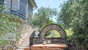A stone staircase leading to a wooden bench and table set against a stone wall, with a bust sculpture above. - Vacation home Diana by Interhome (Labin)