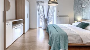 A modern bedroom with a bed, a hanging light fixture, a radiator, and a window with curtains. - Rustica by Interhome (Labin)