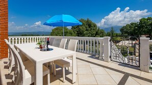A terrace with a table and chairs, a blue umbrella, and a scenic view of trees and mountains. - Rustica by Interhome (Labin)