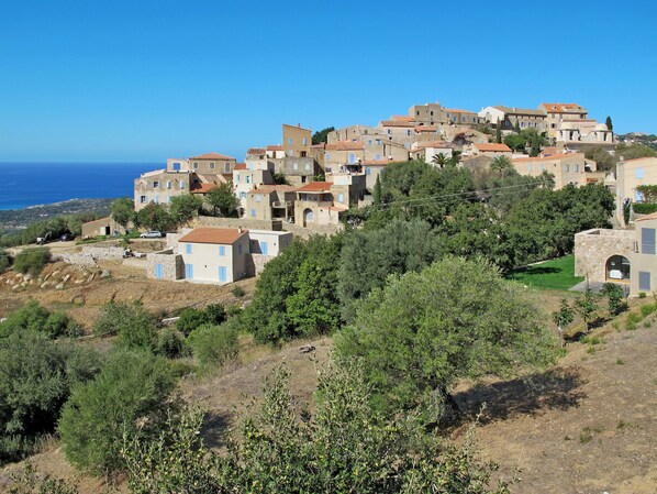 A hillside village with traditional architecture, terraced houses, and a view of the sea.