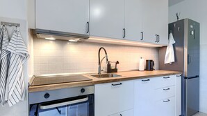Et moderne køkken med hvide skabe, et rustfrit stål køleskab, en indbygget ovn og en træbordplade.