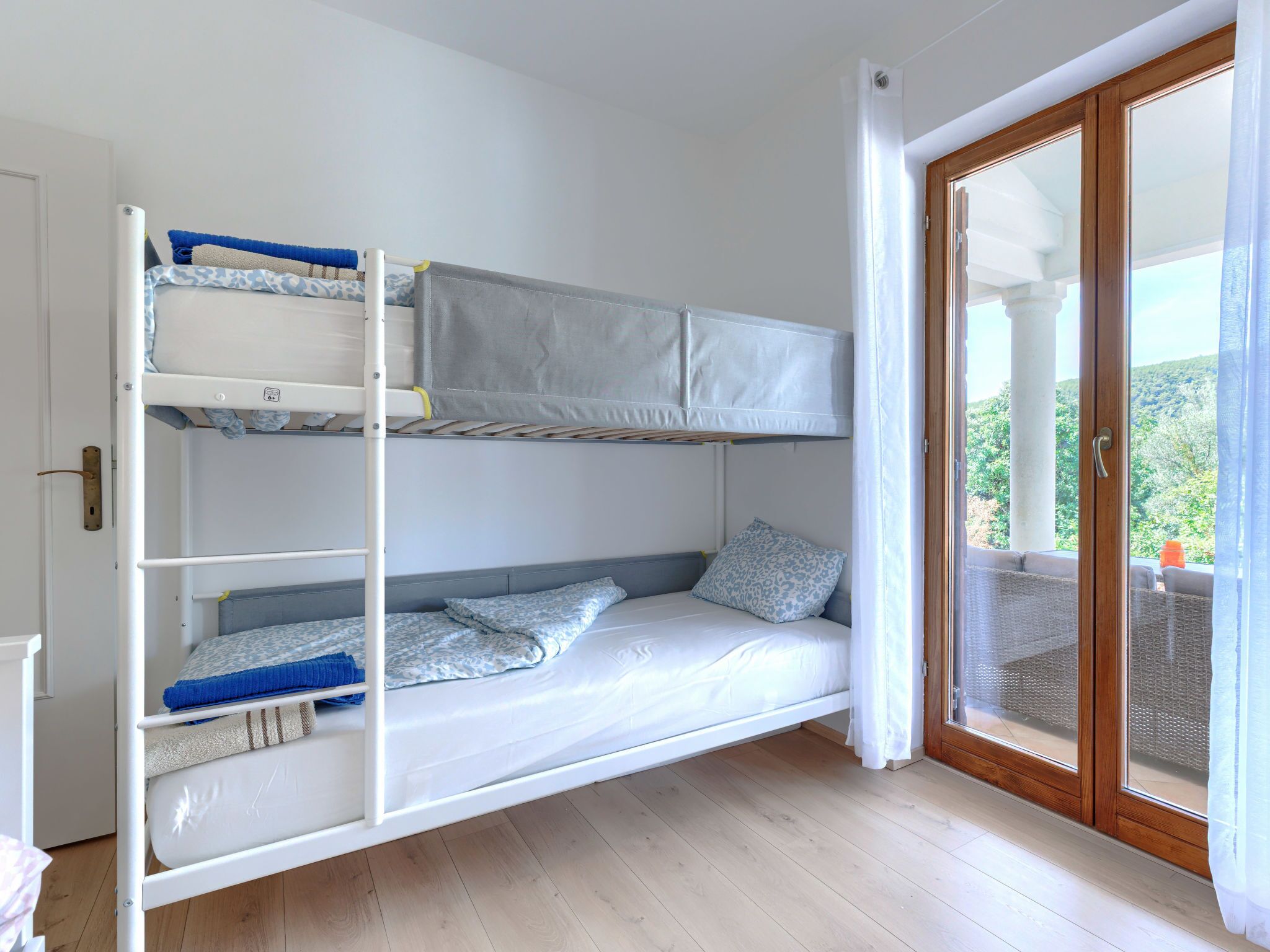 Habitación con literas y puerta corrediza de vidrio que da a un espacio al aire libre.