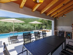 Terrassa exterior amb piscina, caires, ombrel·les i zona de barbacoa.