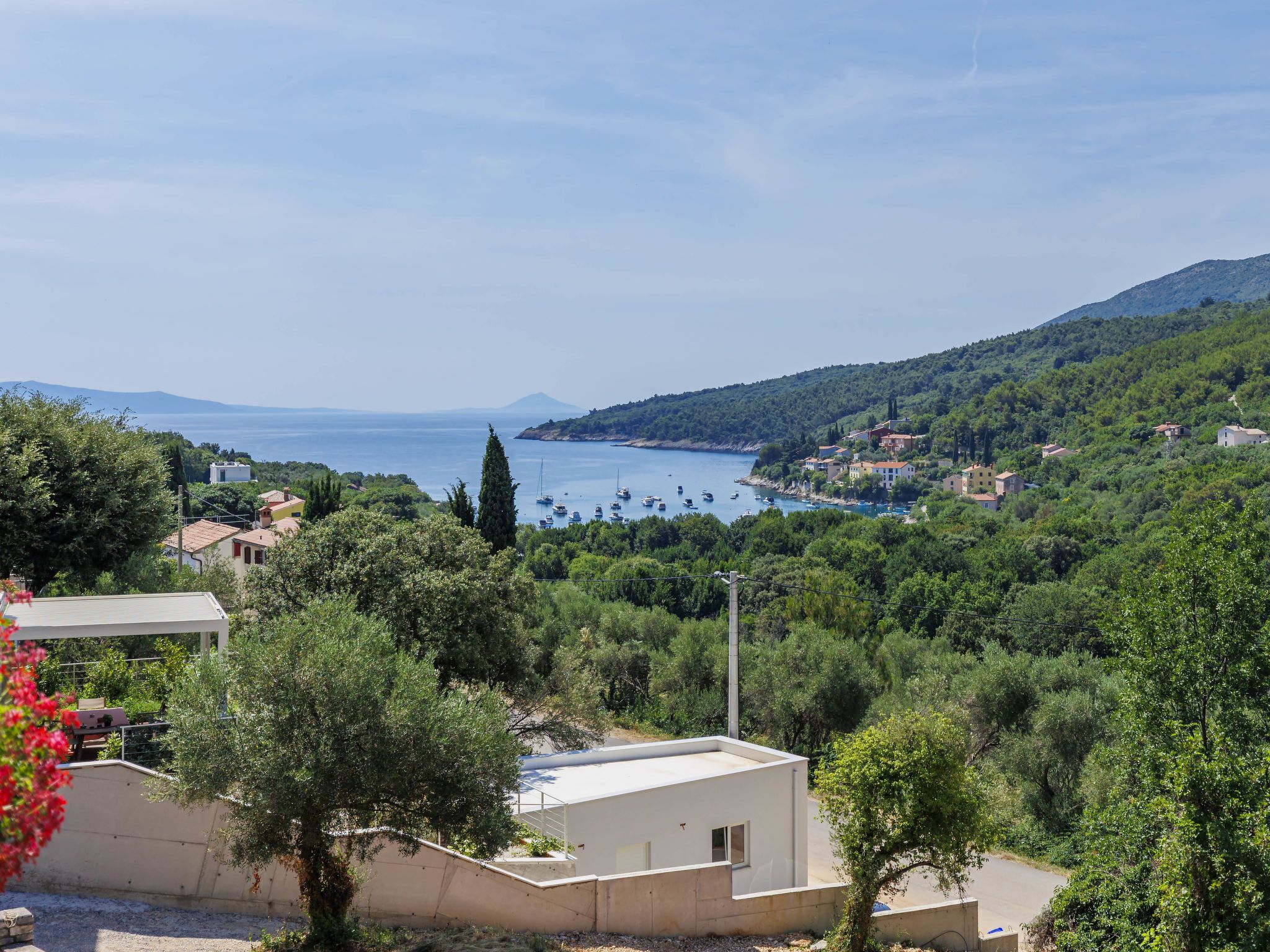 A coastal town with buildings, trees, and a clear view of the sea.
