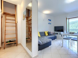 A modern living room with a sofa, TV, and balcony.
