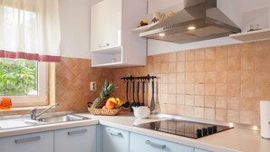Une cuisine moderne avec des meubles blancs, un évier en acier inoxydable et un panier de fruits posé sur le plan de travail.