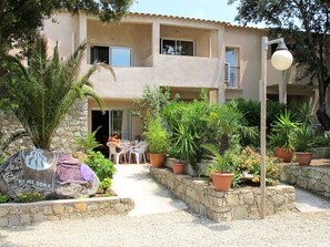 A courtyard with a stone wall, potted plants, and a table with chairs.