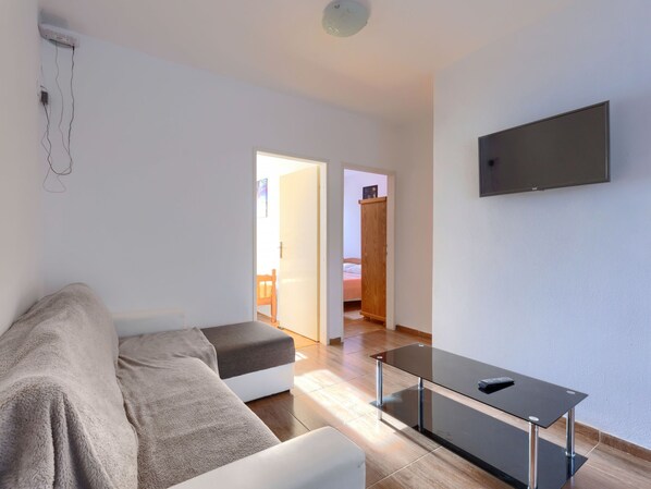 A modern living room with a sofa, a glass-top coffee table, and a flat-screen TV mounted on the wall. - Perkovic by Interhome (Medulin)