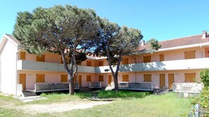 A building with a courtyard, featuring a large tree and multiple balconies.