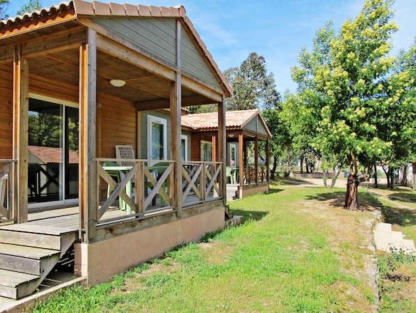 A wooden cabin with a porch, outdoor seating, and a grassy yard.