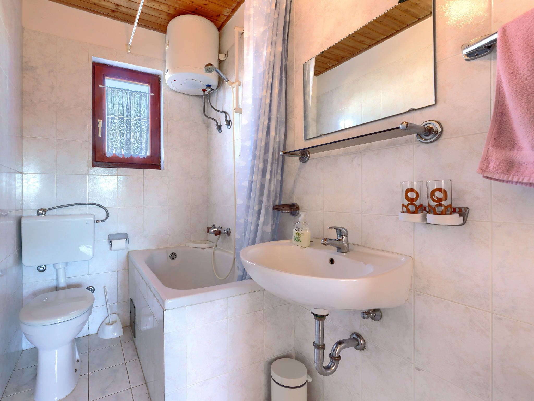 Ein Badezimmer mit Toilette, Badewanne, Waschbecken und Dusche mit Warmwasserbereiter.