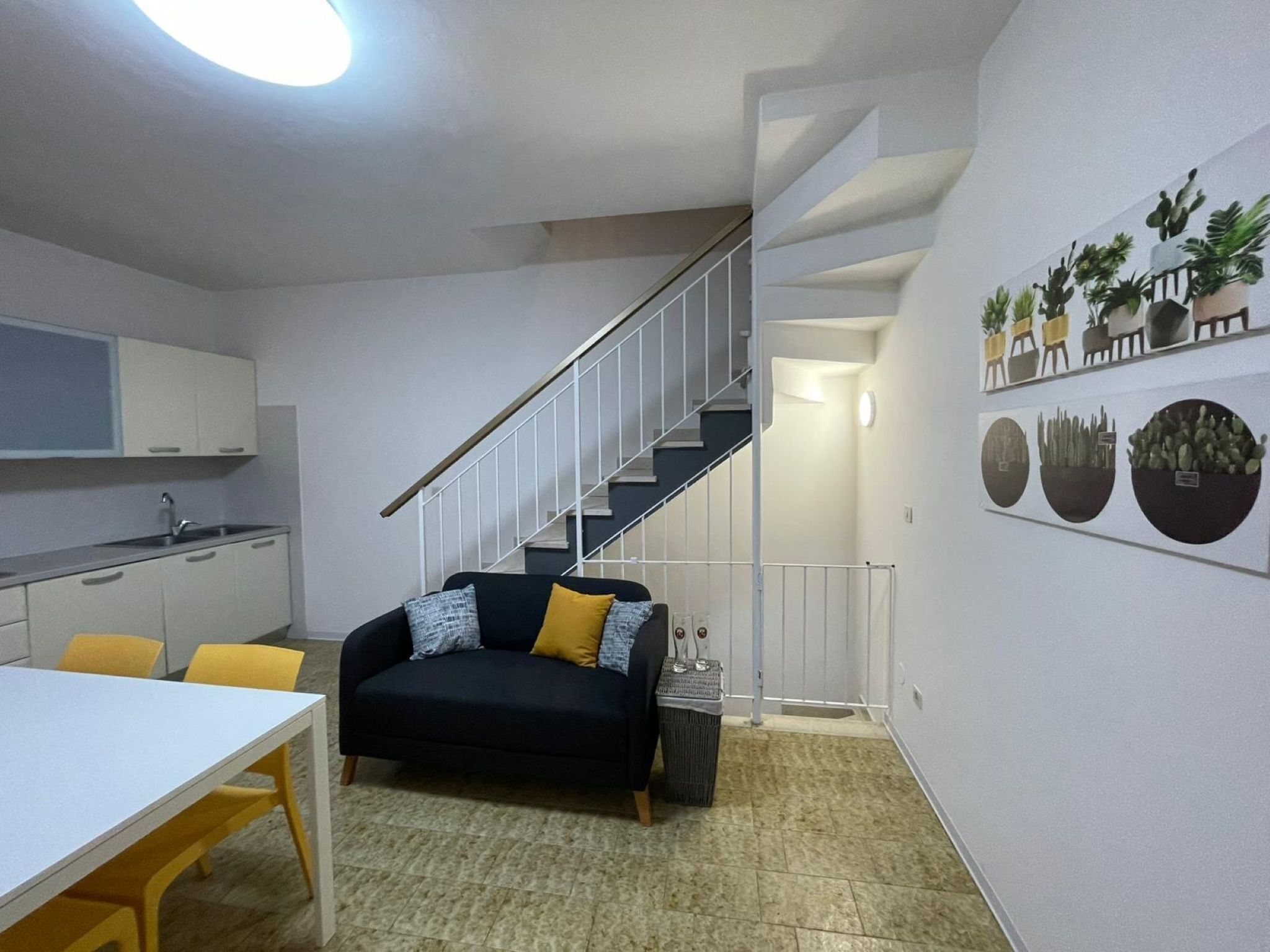 Un espace de vie compact comprenant un coin cuisine, un canapé, une table à manger et un escalier.