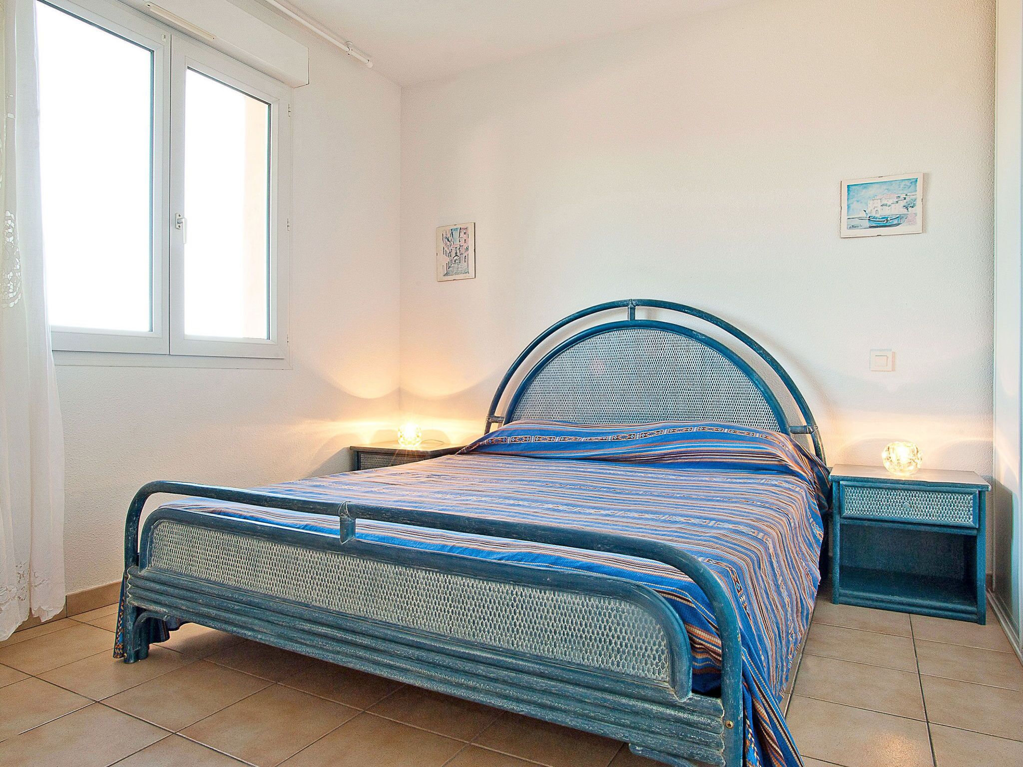 Quarto com cama, janela e quadro pendurado na parede.