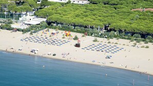 A beach with rows of umbrellas and beach chairs, a playground, and a lifeguard tower.