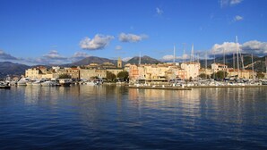 A coastal town with a marina, buildings, and mountains in the background. - Suarella by Interhome (Saint-Florent)