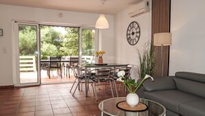 A modern living room with a sofa, a glass coffee table, and a dining area with chairs and a table.