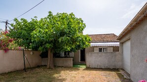 Un patio trasero residencial con un árbol, césped, una pared de concreto y una puerta de garaje.