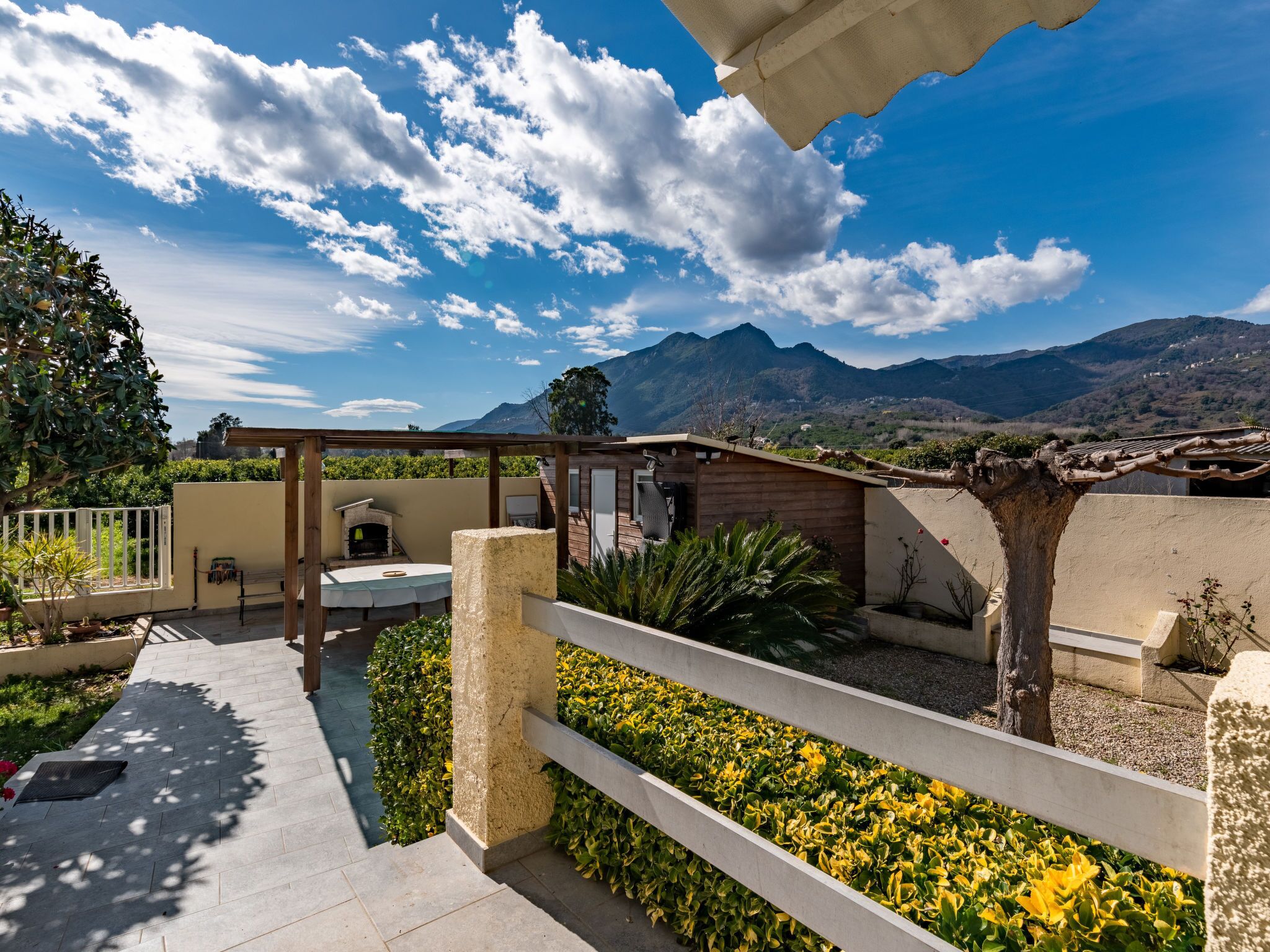 A patio area with a barbecue, seating, and a view of mountains.