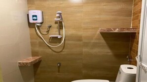 Un petit espace douche fermé, équipé d’un pommeau de douche à main et d’un robinet à main.