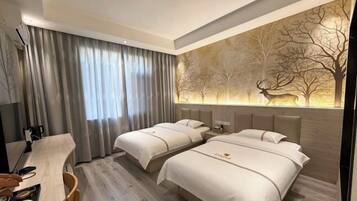 A hotel room with two beds, a desk, and a large window with curtains.