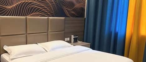 Habitación de hotel con cama, cabecera, mesita de noche y pared con diseño texturizado.