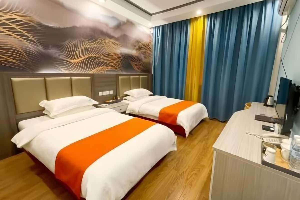 Habitación de hotel con dos camas, un escritorio y un mural grande en la pared.