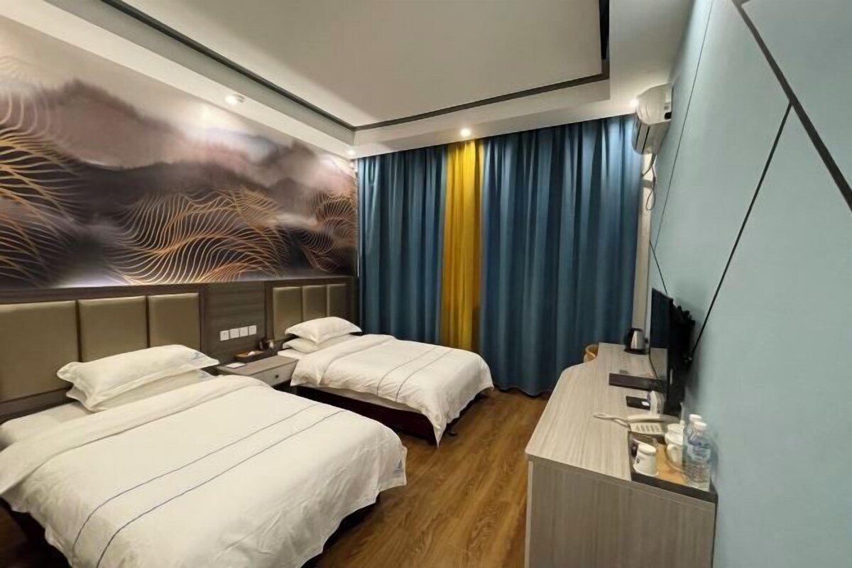 A hotel room with two beds, a desk, and a large wall mural.