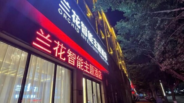 A hotel with illuminated signage in Chinese characters, indicating it is a themed establishment. - Orchid Smart Theme Hotel (Qiaojia)