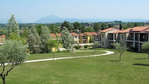 A residential area with modern buildings, a well-maintained lawn, and a distant mountain view.