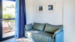 A room with a blue-striped sofa, a sliding glass door, and two framed pictures on the wall.