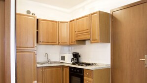 A kitchen with wooden cabinets, a microwave, a coffee maker, and a stove.