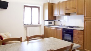 A kitchen with wooden cabinets, a microwave, a stove, and a window.
