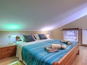 Ein Schlafzimmer mit einem Bett, Nachttischen, einer Lampe und einem Fenster mit Vorhängen.