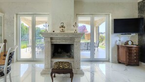 A spacious living room with a fireplace, a television, and a view of the outdoor patio.