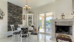 A dining area with a chandelier, a fireplace, and a view of the outdoors.