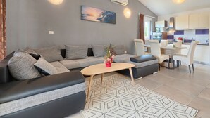 A modern living room with a grey sofa, a wooden coffee table, and a painting on the wall. - Vacation home Goldi by Interhome (Pula/Vodnjan)