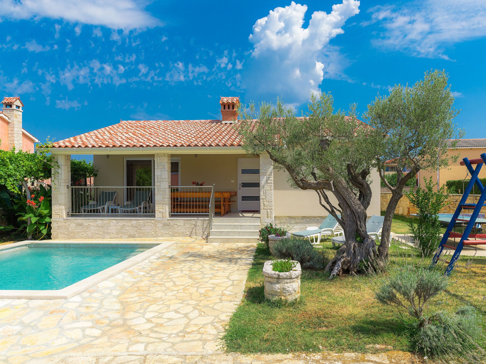 A villa with a swimming pool, outdoor seating, and a garden.