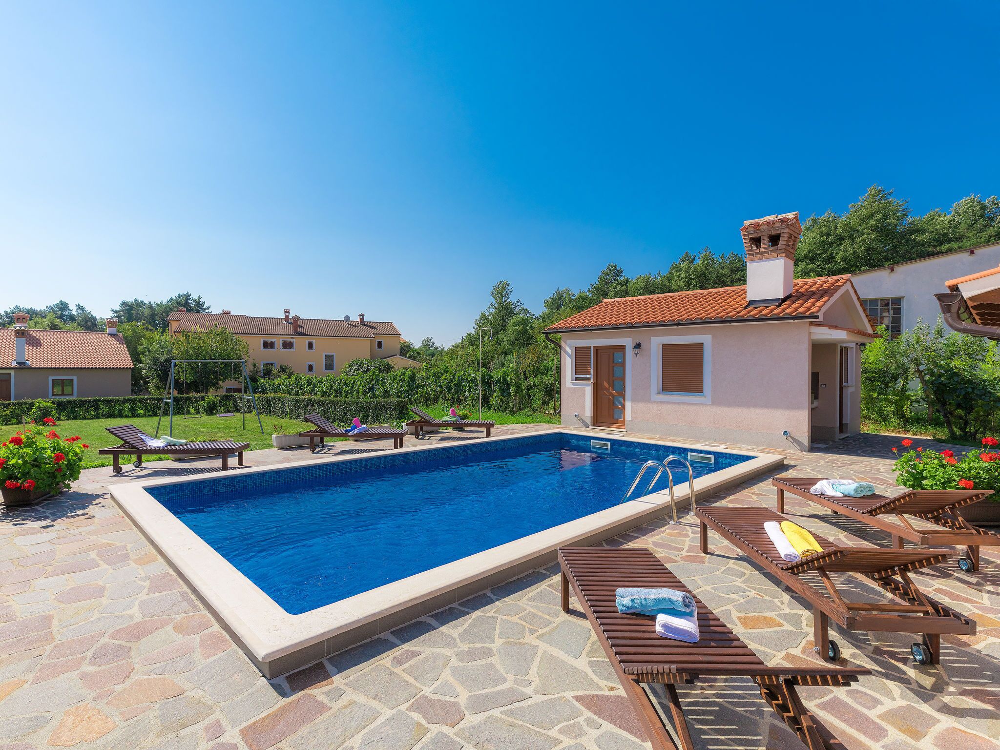 A swimming pool with lounge chairs and a stone patio.