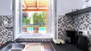 A kitchen with a view of a swimming pool, a coffee maker, and a kettle. - Vacation home Vrt by Interhome (Rovinj)