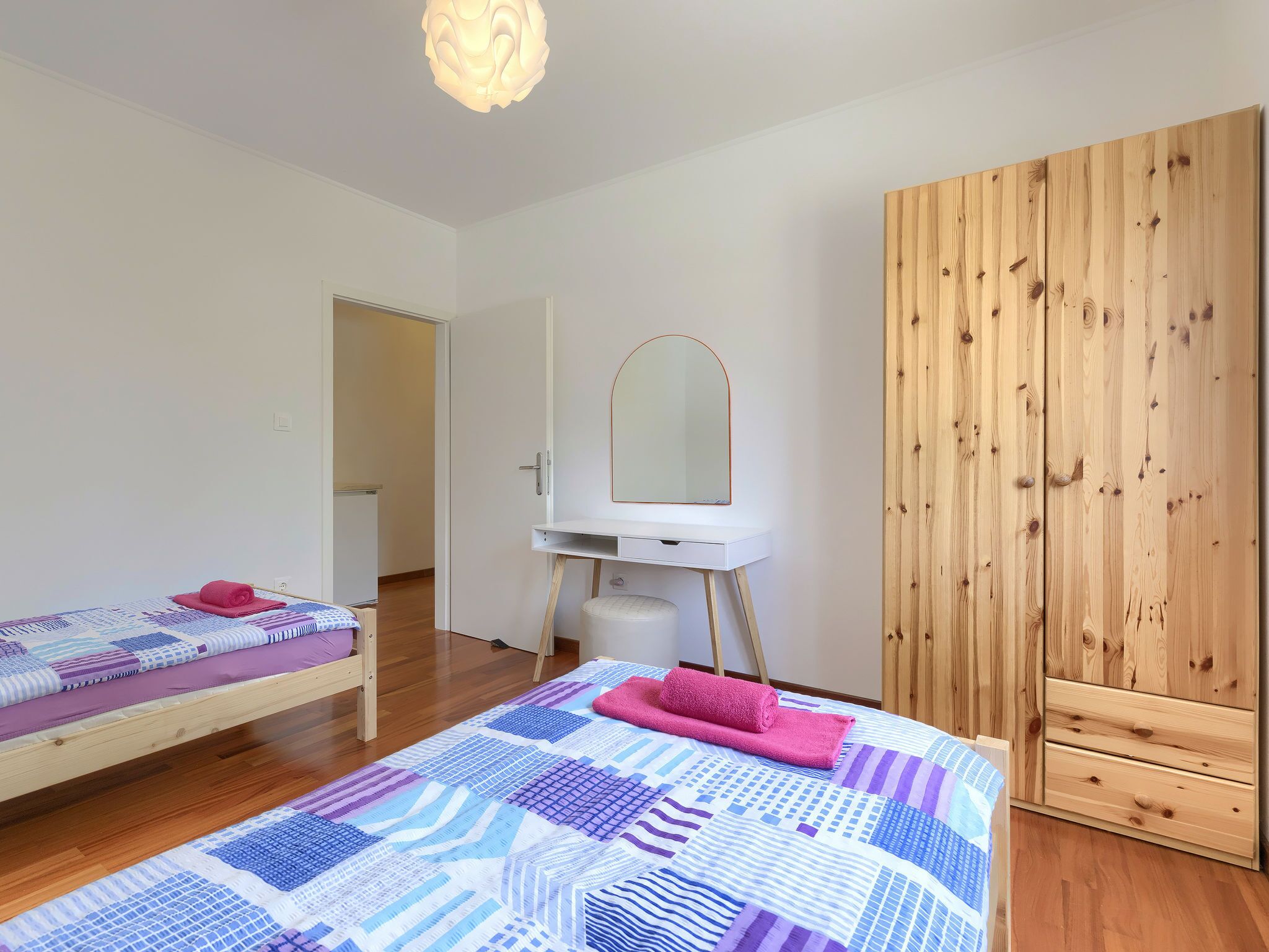 Un dormitorio con una cama, un escritorio pequeño con un espejo y un armario.