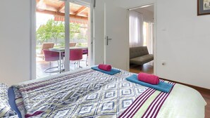 A bedroom with a bed, a sofa, and a dining area with chairs and a table. - Vacation home Vrt by Interhome (Rovinj)